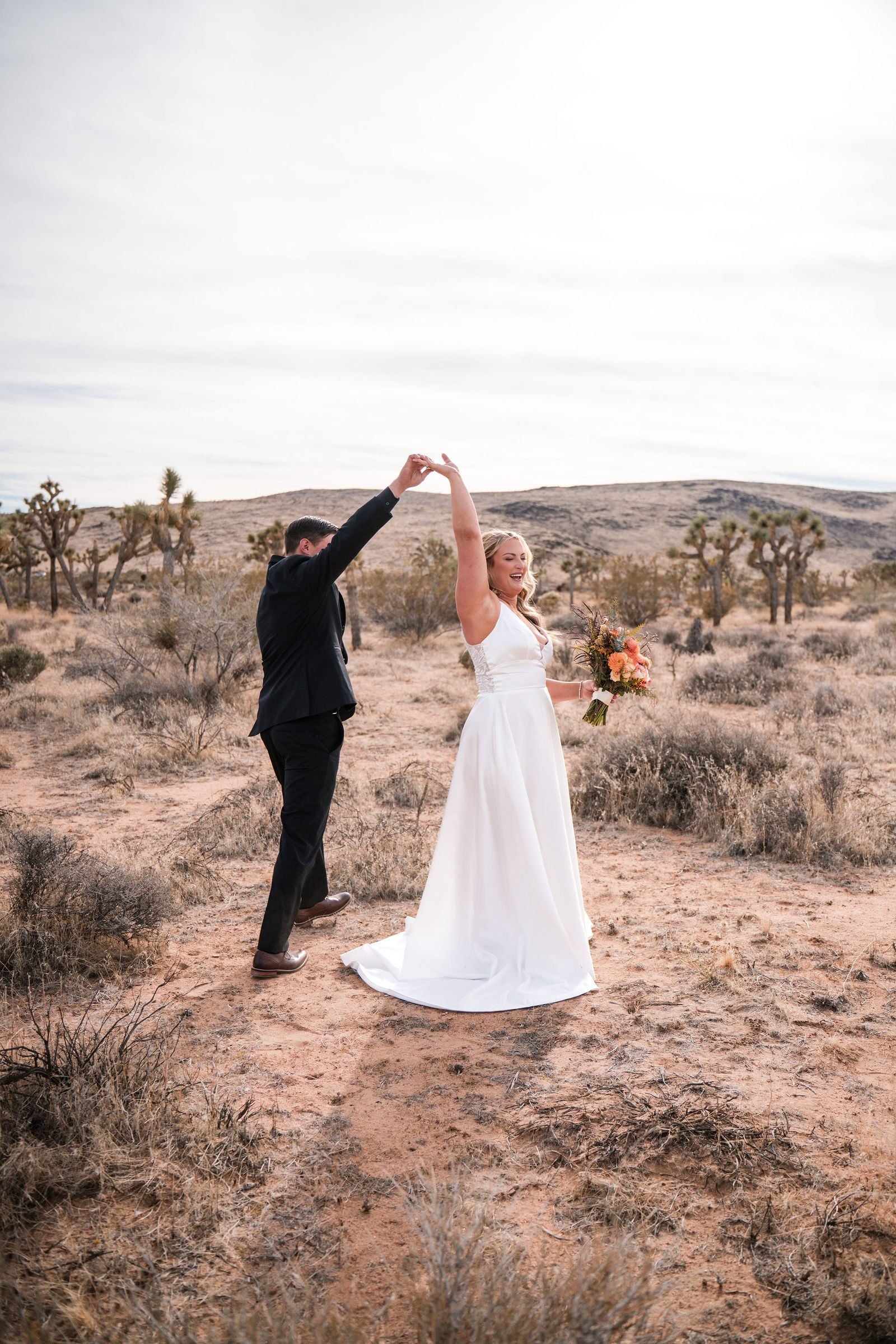 A groom twirling his bride across open desert scrub